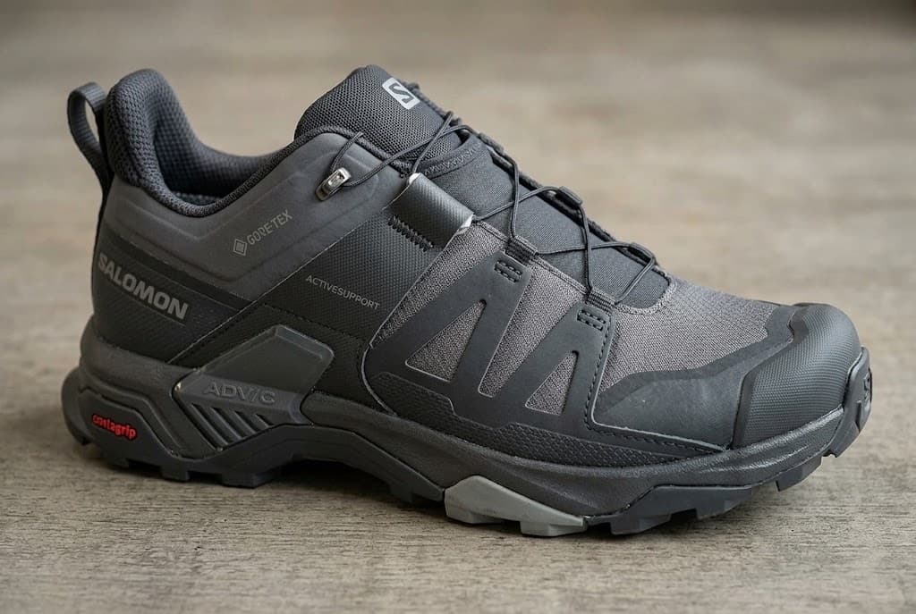 A dark Salomon hiking shoe with visible GORE-TEX, Active Support and Contagrip markings.